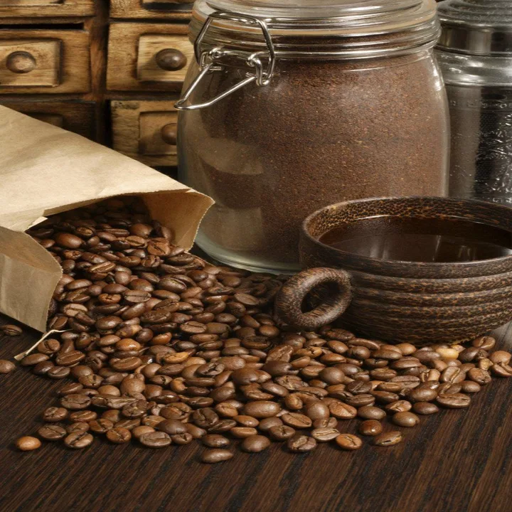 Coffee beans spilled beside a jar and cup