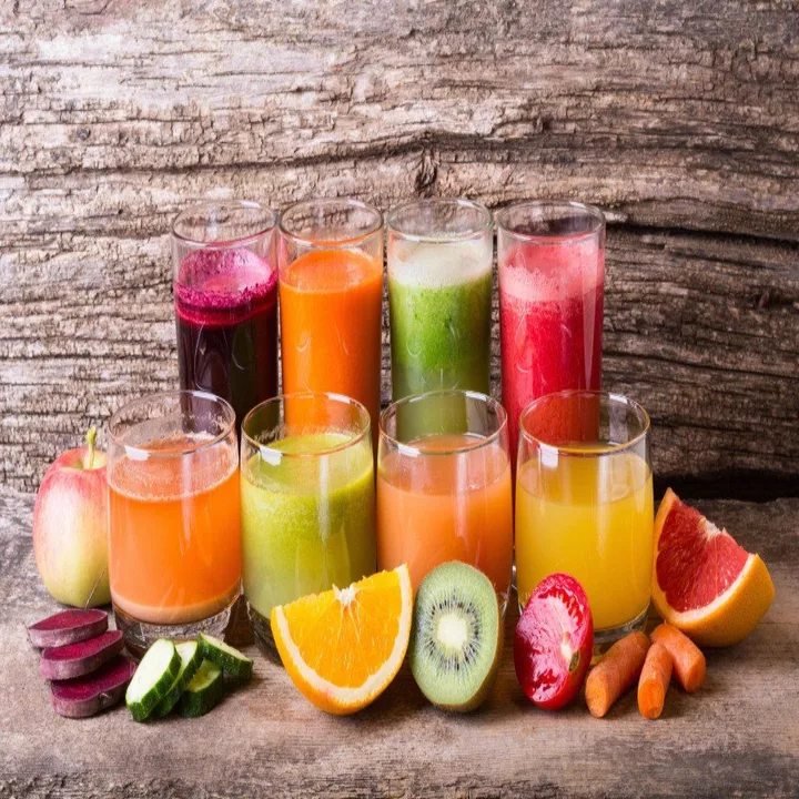 Glasses of fresh raw juice surrounded by fruit and vegetables